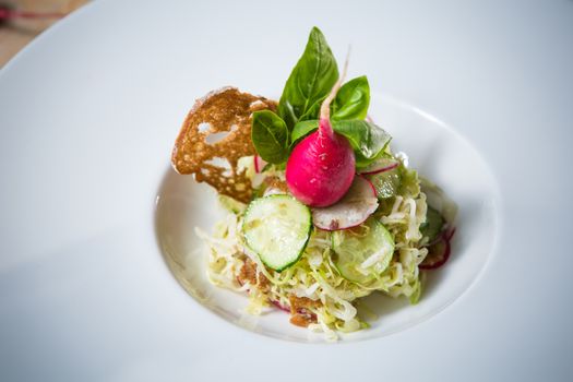 Salad from cabbage, herbs, cucumber, onion and radish in bowl on green wooden background. Coleslaw. Selective focus.