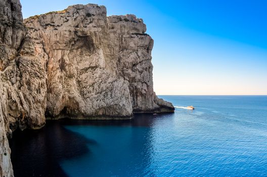 Ocean rocky landscape with the boat, near Neptune's cave, Sardinia, Italy