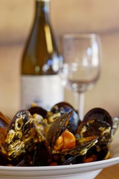 mussels on plate with wine bottle and glass