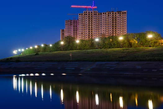 Evening view of the residential complex under construction high-rise buildings by the river