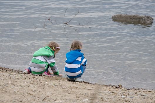 Two children enthusiastically walk along the river bank