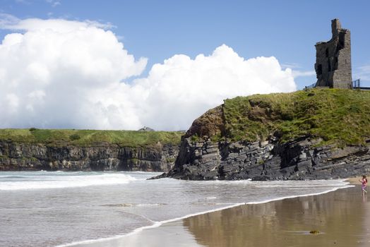 young child on the beach with cliffs and castle on ballybunion beach county kerry ireland