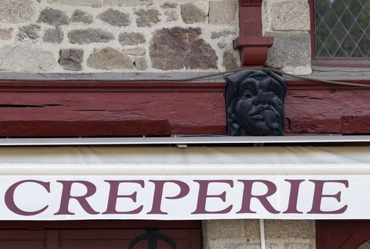 A sign on the wall for a resturant with this wooden carved head