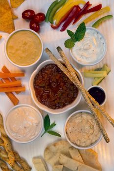 A selection of party dips with bread sticks, pita bread and other crudites.