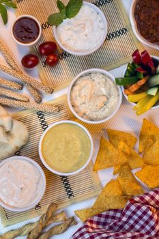 A selection of party dips with bread sticks, pita bread and other crudites.