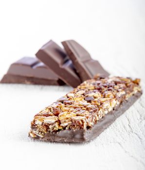 granola bar with chocolate on white wooden background