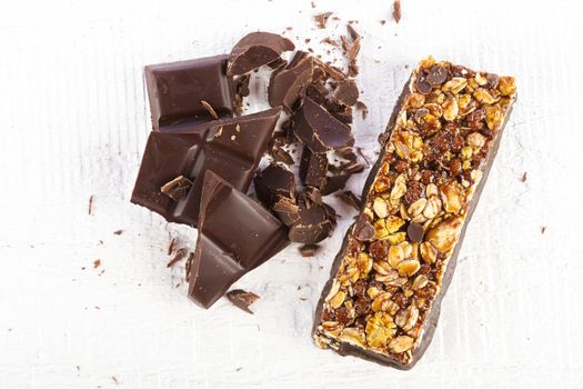 granola bar with chocolate on white wooden background