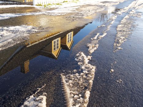 Winter concept background image house reflected in water pond and snow on the road  