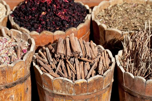 cinnamon sticks and  dried hibiscus petals in wooden container on street stall in tropical country