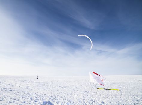 Kite boarder in snowy countryside field with cloudscape background, winter scene