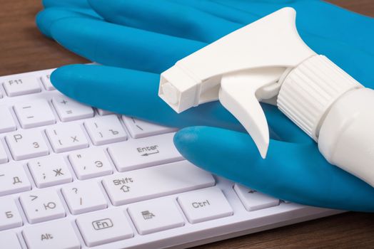 Airbrush with rubber gloves and keyboard on brown wooden table, side view