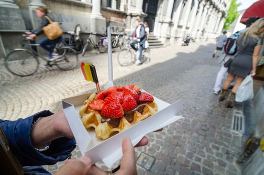 Belgium waffle with chocolate sauce and strawberries, Bruges city background