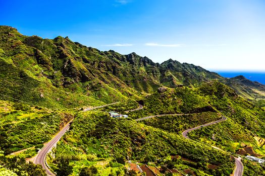 Green mountains or rocks valley with winding road and sky with ocean on horizon landscape in Tenerife Canary island, Spain at summer