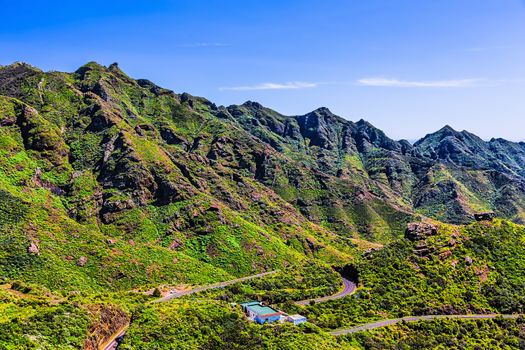 Green mountains or rocks valley with winding or serpantine road and sky landscape in Tenerife Canary island, Spain at summer or spring