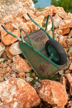 Green Wheelbarrow on red rocks closeup photo