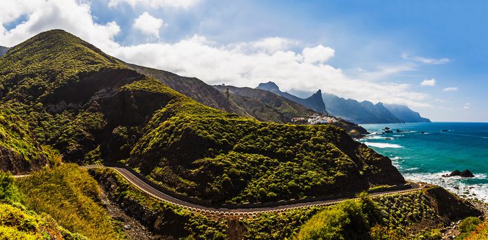 Winding road near coast or shore of Atlantic ocean with mountains and blue sky with clouds and skyline or horizon panorama landscape in Tenerife Canary island, Spain at spring or summer