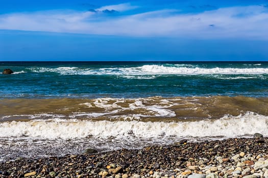 Wild stone beach on coast or shore of the Atlantic ocean with waves and sky with clouds and skyline or horizon in Tenerife Canary island, Spain at spring or summer