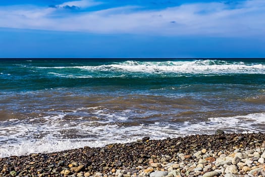 Wild stone beach on coast or shore of the Atlantic ocean with waves and sky with clouds and skyline or horizon in Tenerife Canary island, Spain