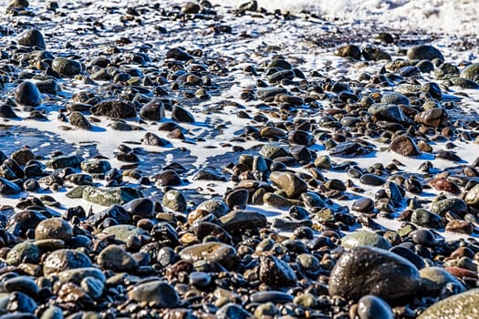 Stones with foam on the beach coast of ocean or sea