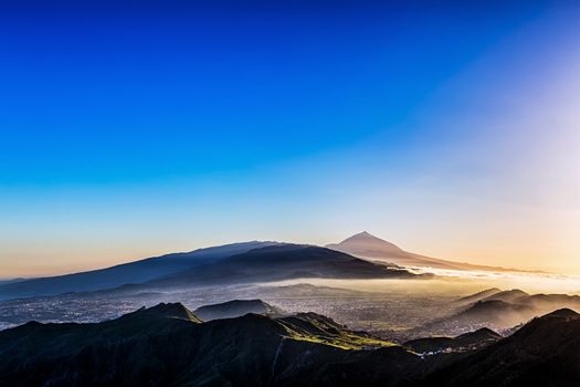 Sunset at evening in mountains and blue sky with haze and Teide volcano on background in Tenerife Canary island, Spain