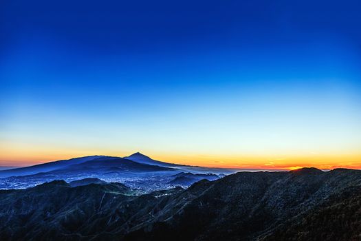 Sunset in mountains and blue sky with haze and Teide volcano on background in Tenerife Canary island, Spain