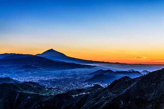 Evening sunset in mountains and blue sky with fog or haze and Teide volcano on background in Tenerife Canary island, Spain