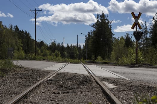 A railway crossing with a cloudy blue sky in the background