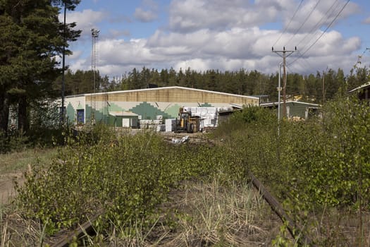 Some bushes on a railway track in front of an industry building