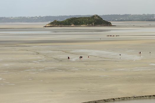 A group of tourists walking to Mont St Michel, Normandy France