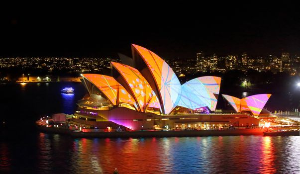SYDNEY, AUSTRALIA - MAY 27, 2015;  The Sydney Opera House in vivid patterns of orange and blue and  harbour reflections during Vivid Sydney