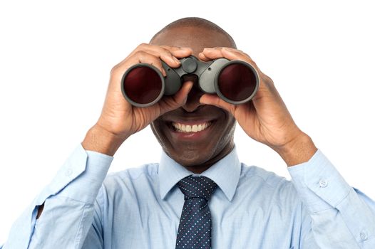 Male executive peers through binoculars over white