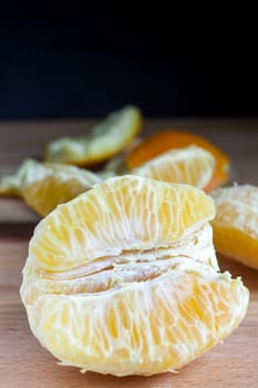 Peeled oranges on a wooded cutting board.