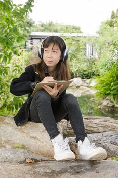 Young beautiful girl are drawing and listen to music in the park