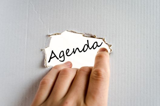 Hand and text on the cardboard background Agenda