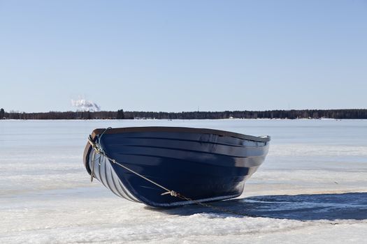 A boat on a frozen lake with a factory in the background