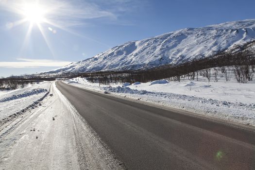 A sunny road with mountains and a great view over the snow covered mountains