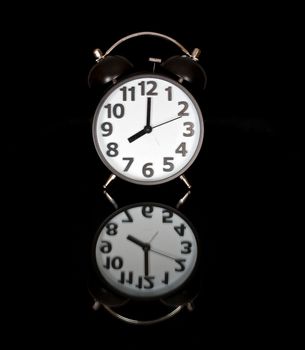 An oldfashioned alarm clock isolates before black background.