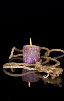 Rope and a burning candle on a black background
