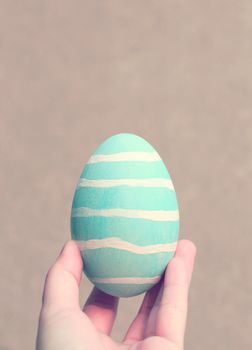 Hand holding painted easter egg with retro filter effect