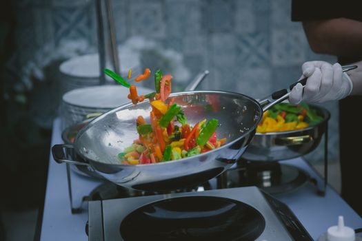 Chef cooking vegetables in wok pan. Shallow dof