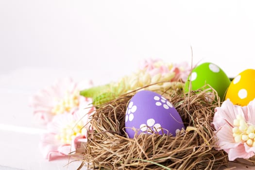 Colorful easter eggs with white points in straw nest