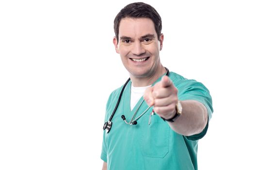 Happy male doctor pointing towards camera over white