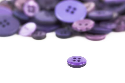 Close up of various purple button scattered on a white surface.