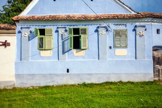 Viscri, Romania - June 23, 2013: Blue painted traditional house with green shutters from Viscri village in Transylvania, Romania