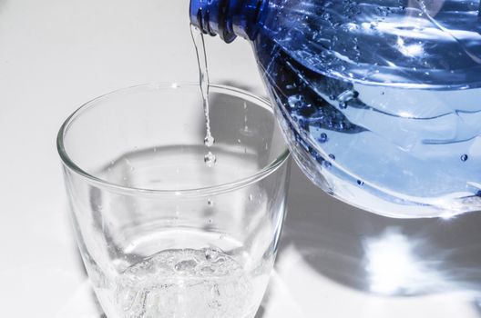 Mineral water from the bottle poured into a glass.