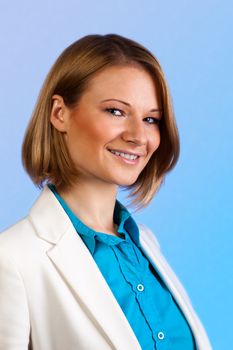 Studio portrait of an attractive young woman in a blue shirt and beige jacket