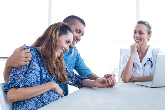 Happy couple looking at ultrasound scan of their baby in medical office