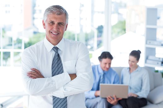 Smiling businessman with arms crossed at office