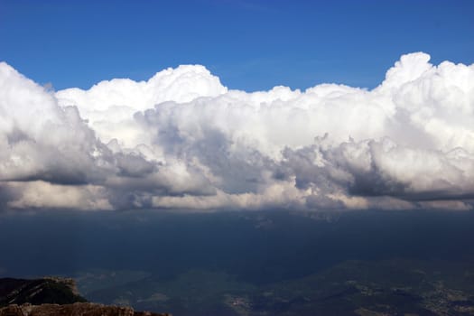Sky blue, dark clouds. View from top of a mountain. Autrans, French Alps, France