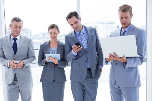 Business colleagues using their multimedia devices in the office